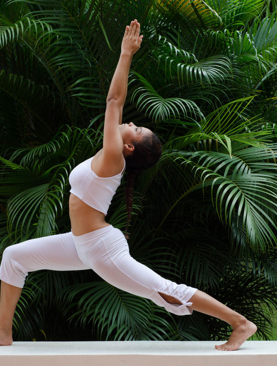 Mulher praticando yoga ao ar livre entre folhagens tropicais